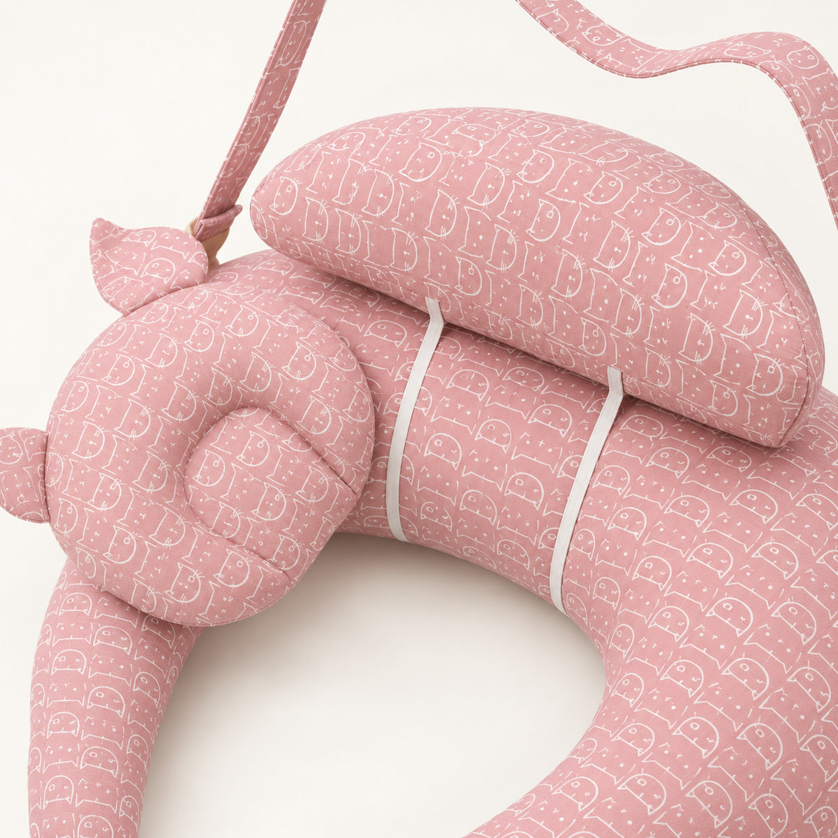 Close-up of pink nursing pillow cushions and cat-print fabric